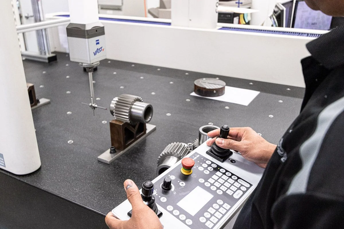 Engineer using a 3D scanner to measure a gear component at a measurement table.