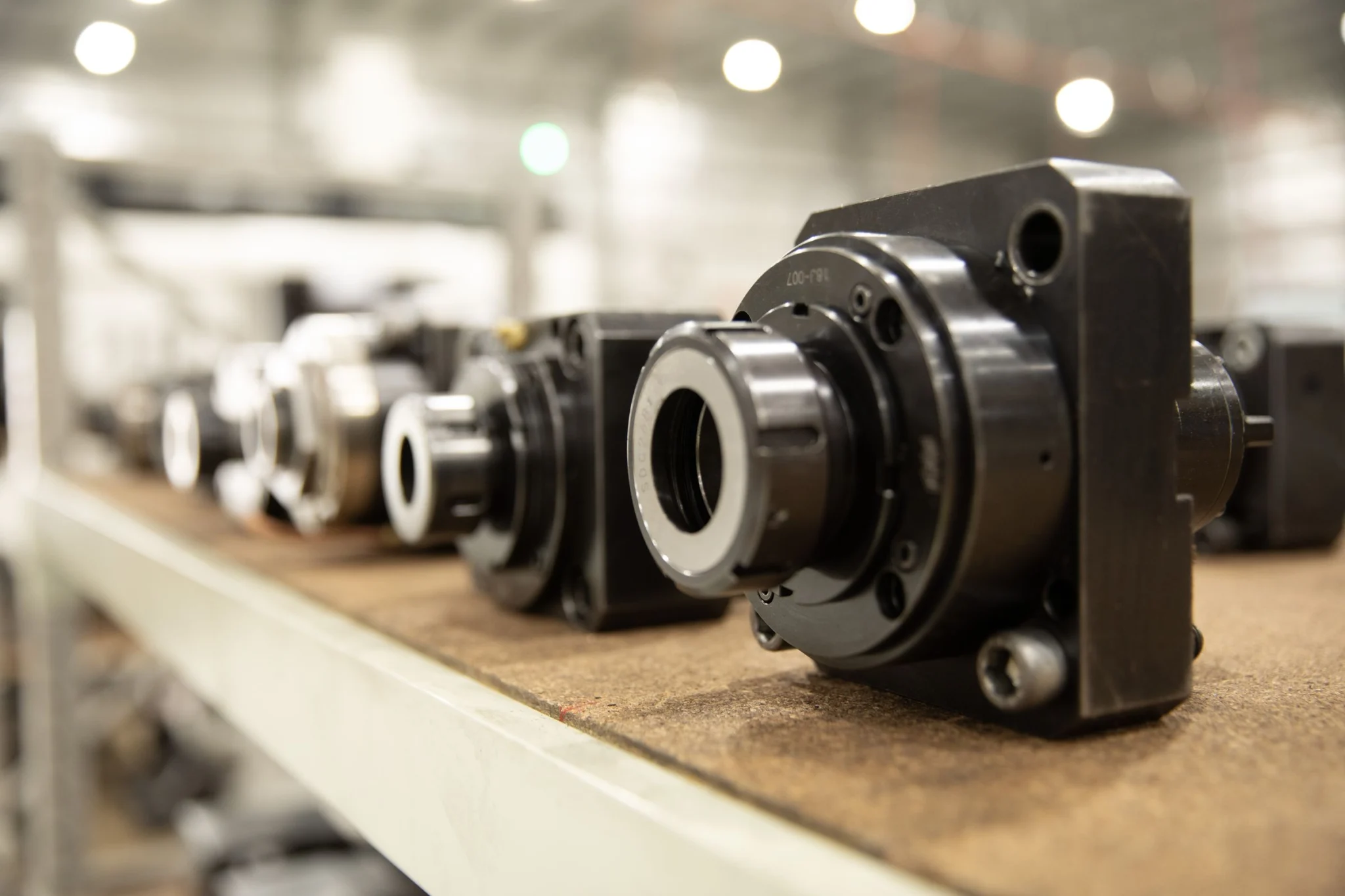 Line of precision-machined drill rig components on workshop bench.